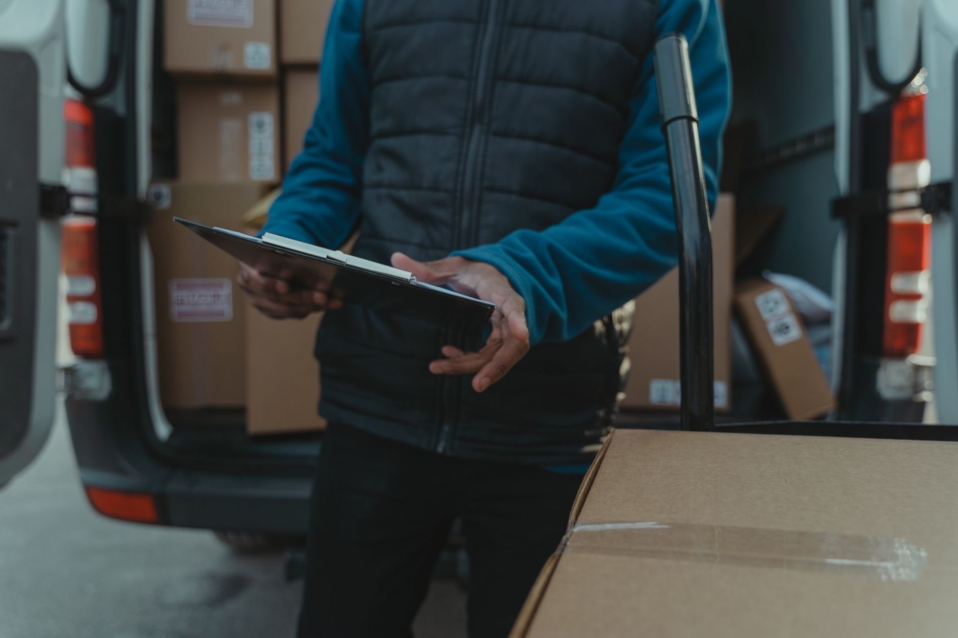 Courier organizes parcel delivery from a van, managing packages efficiently.